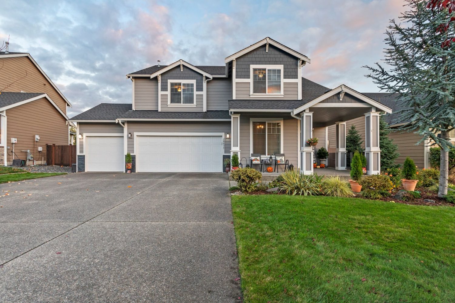 Craftsman-style home with an exposed-aggregate concrete driveway at dusk
